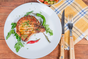 Top view of grilled pork loin on dish, fork, knife