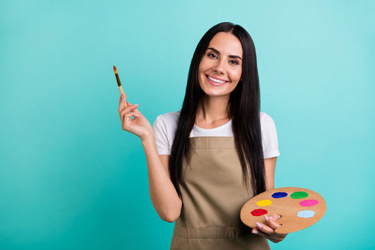 Photo of toothy cheerful beaming cute nice pretty woman looking at you holding colorful palette with brush with hands isolated vivid teal color background