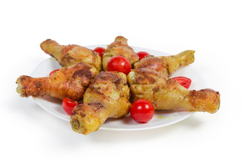 Grilled chicken legs with cherry tomatoes on dish close-up