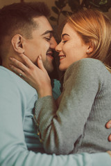 Close up top view of a charming red haired woman with freckles embracing her boyfriend face to face smiling leaning on a bed in their room while traveling .