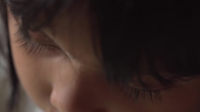 Extreme Close UP Macro Young Asian Girls eyes as she draws indoors alone isolated in dimly lit room