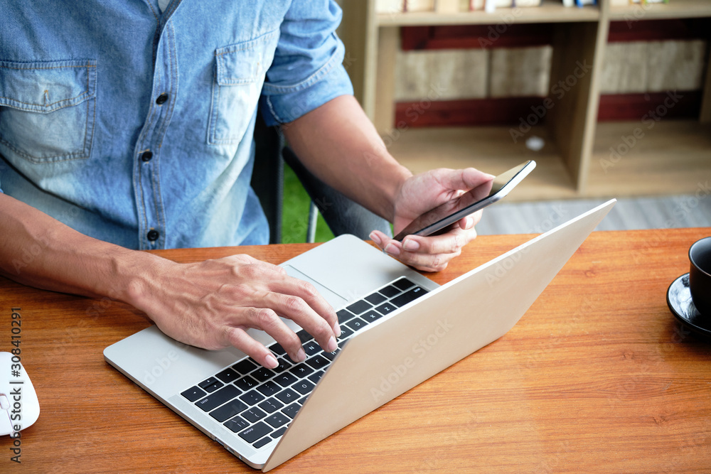 Poster hands of an online business entrepreneur is typing a keyboard on the laptop and holding a cellphone 