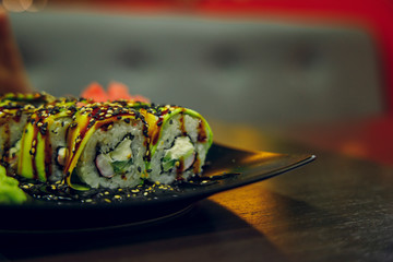 sushi on black plate soft focus food photography in cafe dark interior environment 