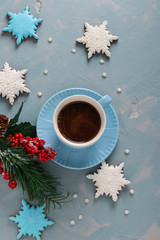 Cup of coffee and gingerbread cookies in the shape of snowflakes on a light blue background, Top view,, vertical orientation