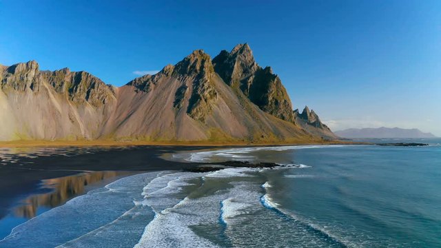 Epic aerial drone view flying over landscape of the black sand beach in Stokksnes. Vestrahorn mountain in the background. Nature and ecology concept background.