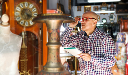 man owner of antiques shop inventorying vintage goods