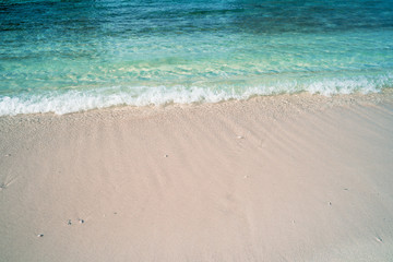 Fototapeta na wymiar Calm waves lap up on the pristine sandy beach of the Maldives