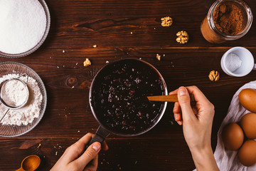 Female's hands mix melted chocolate with nuts