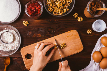 Female hands chop walnuts for baking brownie cake