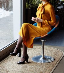 girl in a cafe with a cup of coffee and a hat. beautiful girl with a cup of coffee near the window in a cafe, waiting for a meeting, breakfast