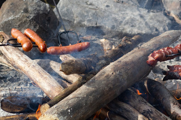 Grilling sausages with BBQ fork on open fire