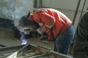 Making a metal fence. Man welding pipe