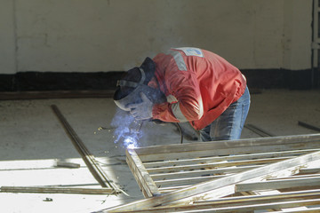 Making a metal fence. Man welding pipe