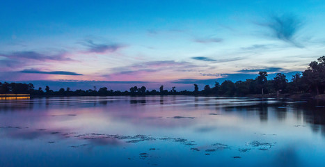 sunrise in the morning in aisa the sky is reflecting on the surface of the water, lake surrounded by the silhouette or trees 