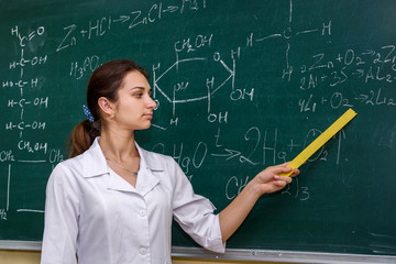 Chemical education. Woman near board explaining to students some material