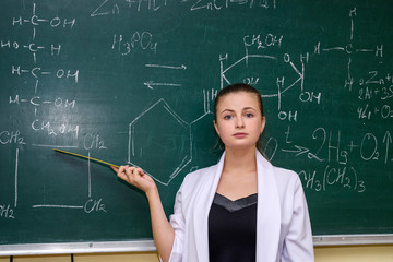 Chemical education. Woman near board explaining to students some material