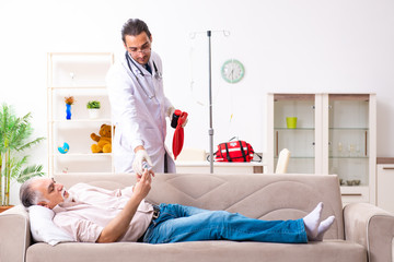 Young male doctor visiting old patient at home
