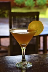 Orange coloured cocktail in martini glass on outdoor bar counter 