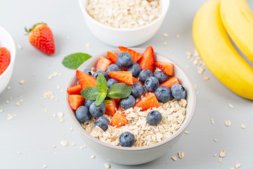 Healthy smoothie bowl with granola, fresh strawberries, blueberries, bananas, yogurt and mint. Healthy food, snack or breakfast. 