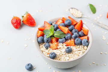 Healthy smoothie bowl with granola, fresh strawberries, blueberries, bananas, yogurt and mint. Healthy food, snack or breakfast. 