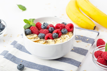 Breakfast smoothie with granola, fresh raspberries, blueberries, bananas, coconut flakes, Chia seeds and mint. Healthy food. 