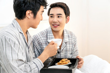 Asian homosexual couple in pajamas having a breakfast in the bed.Concept LGBT gay.