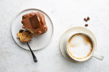 Piece of cake with nuts and chocolate with coffee cup on white background, top view