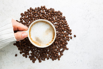 Cup of coffee in womens hand on white background, top view