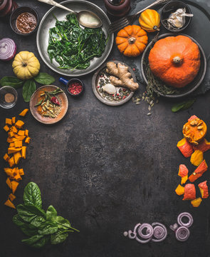 Vegetarian seasonal food background with ingredients for herbs and winter cooking: pumpkin,spinach, ginger, onion. Top view. Frame. Copy space