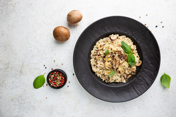 Risotto with mushrooms in a black plate over white background, top view