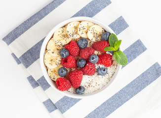 Breakfast smoothie with granola, fresh raspberries, blueberries, bananas, coconut flakes, Chia seeds and mint. Healthy food. Top view. 