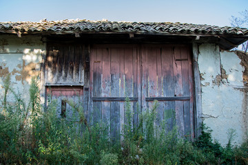Old abandoned house's facade, damaged painted wooden door/window, bulding exterior
