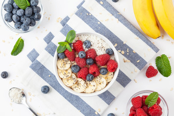 Breakfast smoothie with granola, fresh raspberries, blueberries, bananas, coconut flakes, Chia seeds and mint. Healthy food. Top view. 