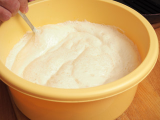 Mixing batter after rising. Making yeast pancakes (crepes).