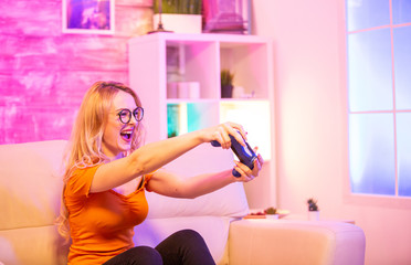 Beautiful blonde girl excited while playing video games