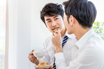 Relax and tea time.Portrait of Asian homosexual couple eating cookie and enjoy funny moment.Concept...