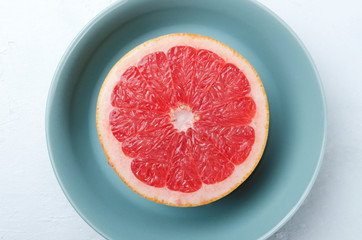 Top view of half grapefruit in the blue bowl on the center of white table 