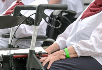 Fototapeta premium Zbliżenie na ręce starszej kobiety w grupie i walker na pierwszym planie - selektywne fokus