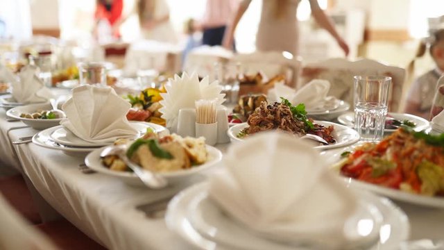 Beautifully served banquet table with different food snacks and appetizers in the sun on corporate christmas birthday party event or wedding celebration. Decorated catering in white interior.
