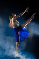 girl dancer in a jump and a beautiful pose on a blue background