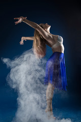 girl dancer in a jump and a beautiful pose on a blue background