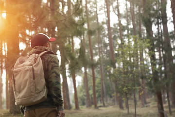 Naklejka premium Traveler man with backpack standing near tropical jungle at sunny day