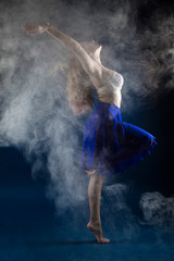 Fototapeta na wymiar girl dancer in a jump and a beautiful pose on a blue background