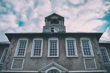 Old house with attic on the background of the cloudy blue sky. The facade of the building in the retro style of European architecture