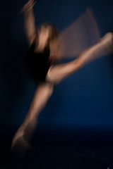 Fototapeta na wymiar girl dancer in a jump and a beautiful pose on a blue background