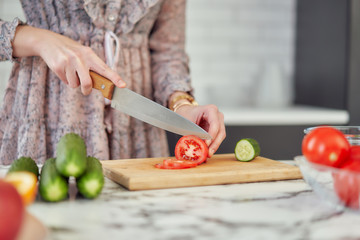 healthy eating, diets, vegetarian cuisine and cooking concept - close-up of a knife cuts tomatoes and cucumbers at home