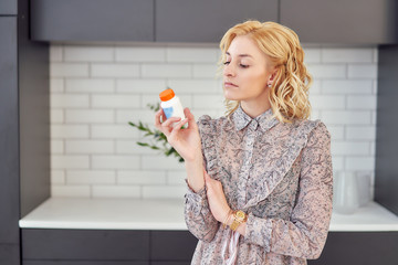 female nutritionist reads instructions on packaging vitamins in bottles
