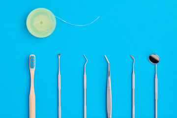Dentist tools over blue background top view copy space flat lay. Tooth care, dental hygiene and health concept.