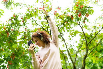 Young girl listens to music with big earphones and dances
