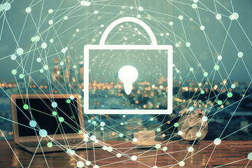 Double exposure of desktop with computer and lock icon hologram. Concept of data safety.